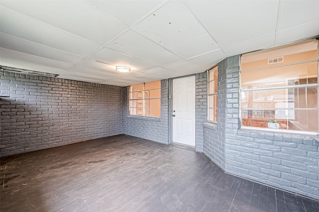 unfurnished room featuring hardwood / wood-style flooring and brick wall