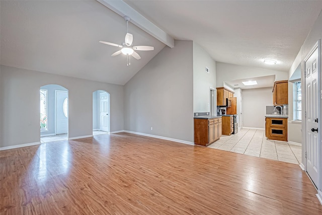 unfurnished living room with sink, high vaulted ceiling, light hardwood / wood-style flooring, beamed ceiling, and ceiling fan