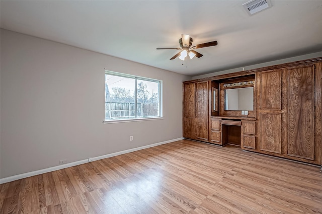 unfurnished bedroom with ceiling fan, built in desk, and light wood-type flooring