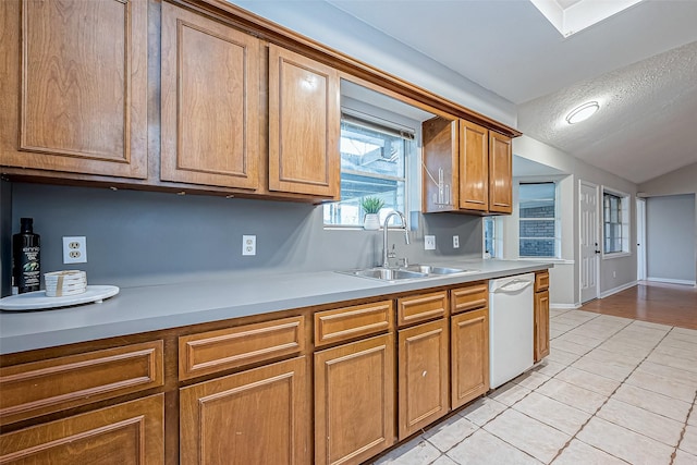 kitchen with lofted ceiling, sink, a textured ceiling, light tile patterned floors, and dishwasher