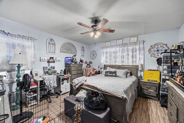 bedroom with ceiling fan, light hardwood / wood-style flooring, and a textured ceiling