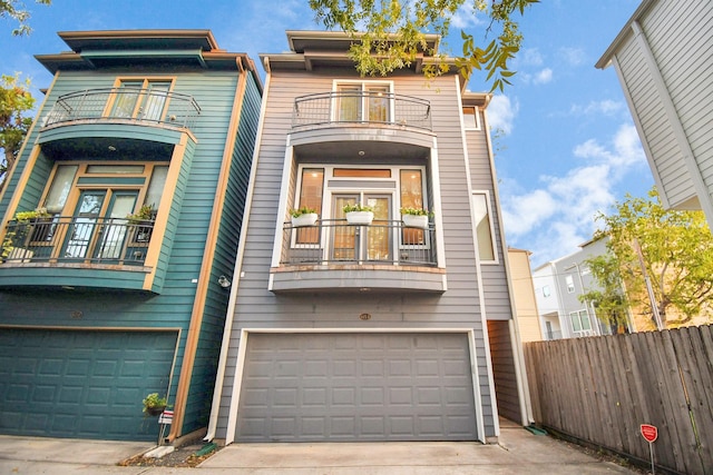 view of property with concrete driveway, a balcony, an attached garage, and fence