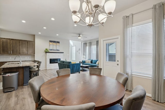 dining area featuring ceiling fan, a fireplace, light hardwood / wood-style floors, and sink