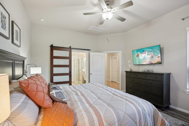 bedroom with dark hardwood / wood-style floors, ceiling fan, ensuite bathroom, and a barn door