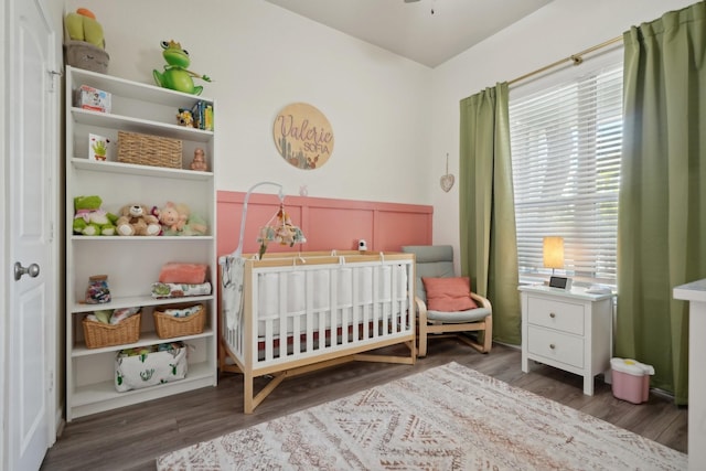 bedroom with multiple windows, dark hardwood / wood-style flooring, and a crib