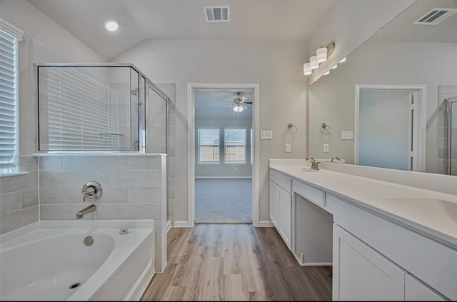 bathroom with hardwood / wood-style flooring, ceiling fan, vanity, vaulted ceiling, and separate shower and tub