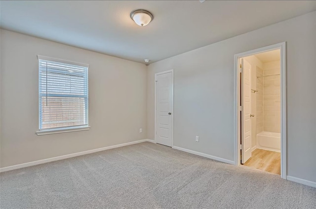 unfurnished bedroom featuring light colored carpet and ensuite bathroom