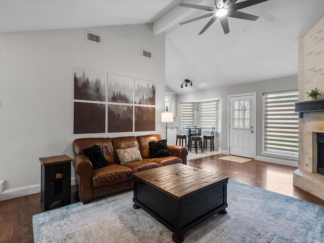 living room featuring ceiling fan, high vaulted ceiling, wood-type flooring, a large fireplace, and beamed ceiling