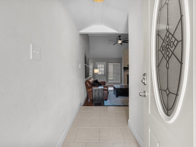 corridor featuring lofted ceiling and light tile patterned floors