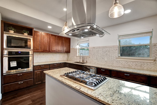 kitchen with sink, light stone counters, hanging light fixtures, island exhaust hood, and stainless steel appliances