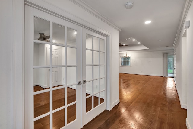 corridor with crown molding, dark hardwood / wood-style floors, a raised ceiling, and french doors