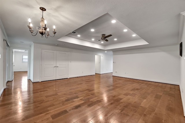 spare room featuring hardwood / wood-style floors, ceiling fan with notable chandelier, a raised ceiling, and a barn door