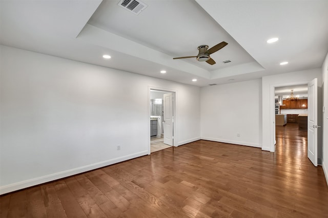 interior space with ceiling fan with notable chandelier, hardwood / wood-style floors, and a tray ceiling