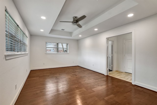 unfurnished room with hardwood / wood-style floors, ceiling fan, and a tray ceiling