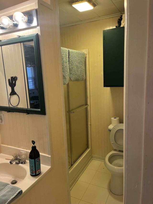 bathroom featuring tile patterned floors, toilet, sink, crown molding, and a shower with door