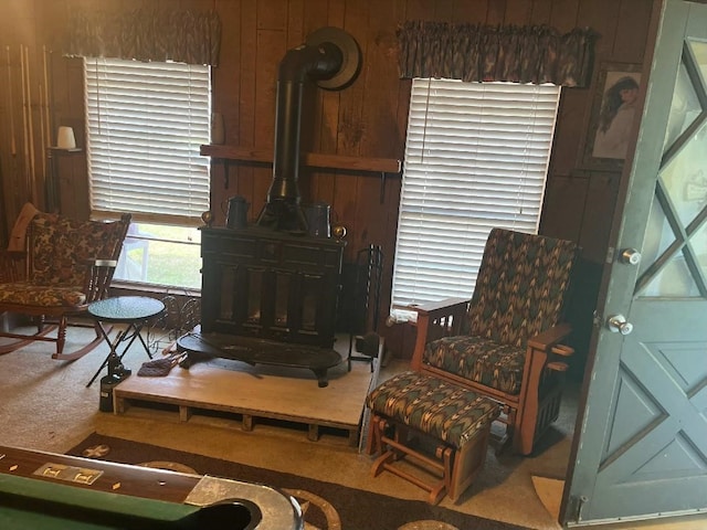 sitting room with wood walls, carpet floors, and a wood stove