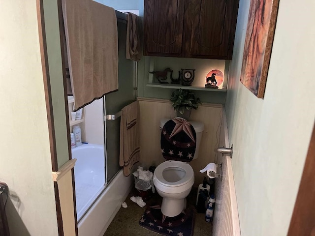 bathroom with toilet and bath / shower combo with glass door