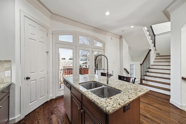 kitchen featuring an island with sink, light stone countertops, sink, and stainless steel dishwasher