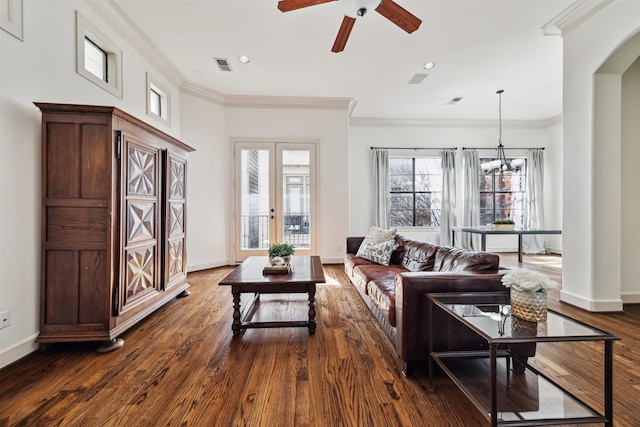 living room featuring crown molding, dark wood-type flooring, and ceiling fan with notable chandelier