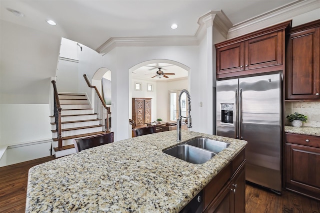 kitchen featuring dark hardwood / wood-style floors, an island with sink, sink, light stone counters, and stainless steel refrigerator with ice dispenser