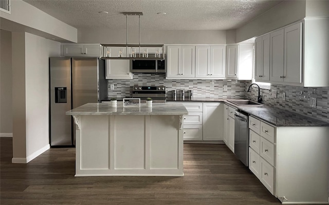 kitchen with dark wood-type flooring, a sink, backsplash, white cabinetry, and appliances with stainless steel finishes