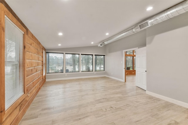 spare room featuring light wood-type flooring and lofted ceiling