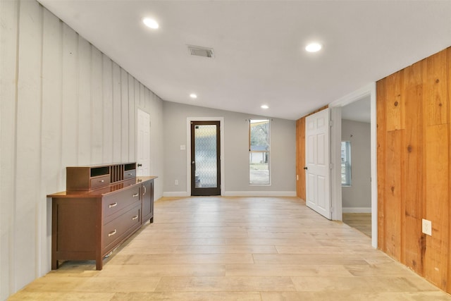 foyer entrance featuring wooden walls, light hardwood / wood-style floors, and lofted ceiling