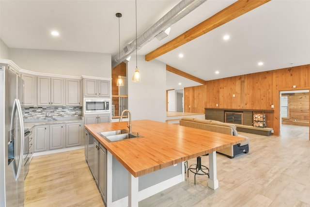 kitchen featuring a kitchen island with sink, stainless steel appliances, sink, gray cabinets, and pendant lighting