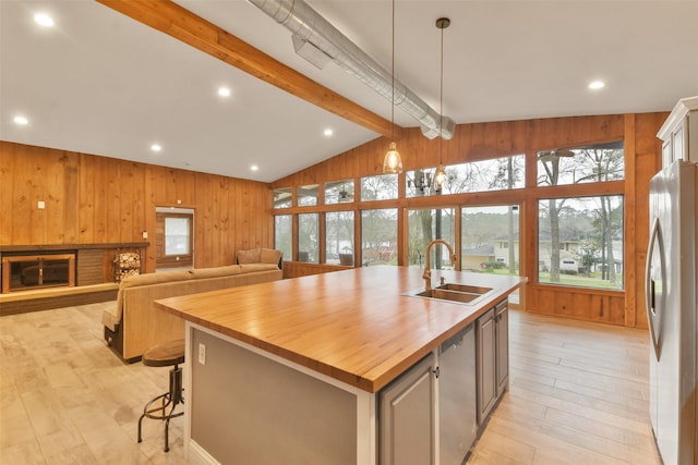 kitchen with a center island with sink, butcher block counters, stainless steel appliances, pendant lighting, and sink