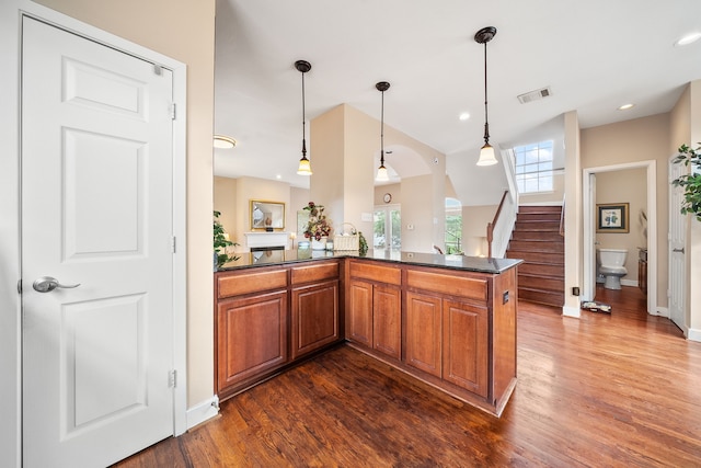 kitchen featuring dark wood-type flooring, decorative light fixtures, kitchen peninsula, and sink