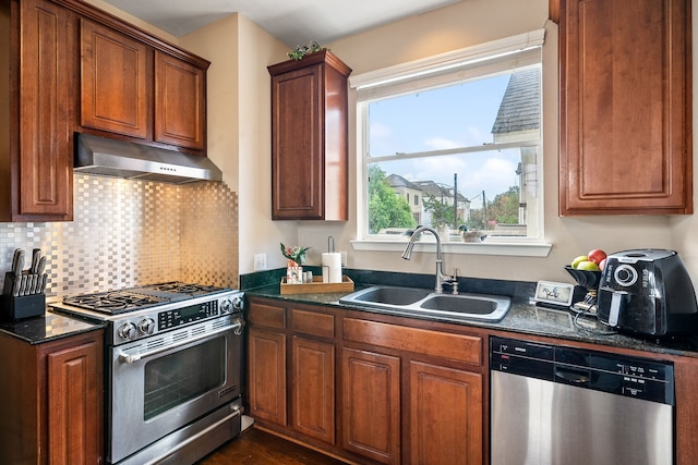 kitchen featuring stainless steel appliances, tasteful backsplash, sink, and dark stone counters