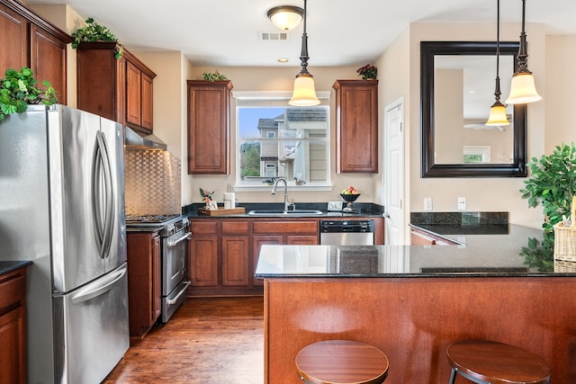 kitchen with stainless steel appliances, sink, a kitchen bar, and decorative light fixtures