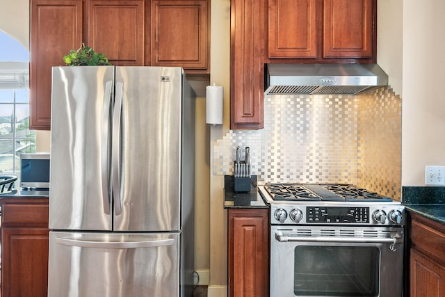 kitchen with backsplash, dark stone counters, wall chimney exhaust hood, and appliances with stainless steel finishes