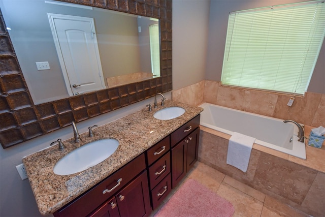 bathroom with tiled tub, vanity, and tile patterned flooring