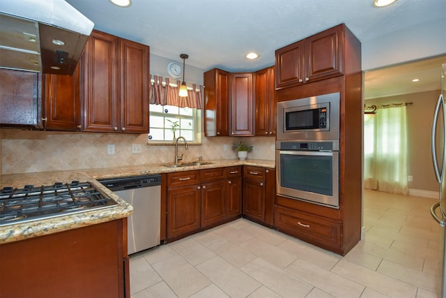 kitchen with appliances with stainless steel finishes, pendant lighting, sink, exhaust hood, and light stone countertops