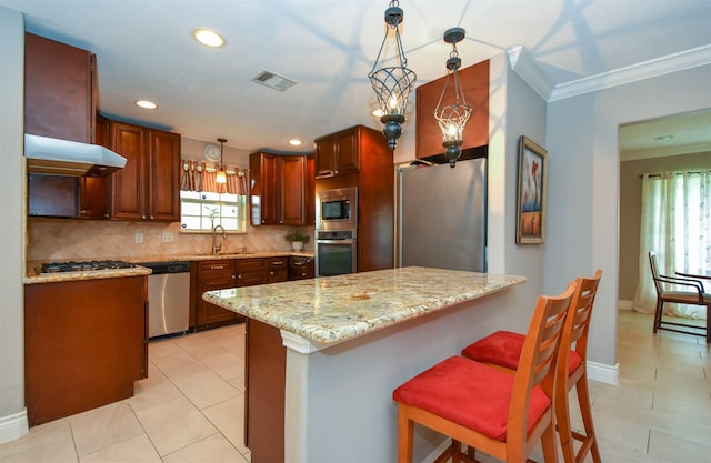 kitchen with light stone counters, stainless steel appliances, decorative light fixtures, and sink