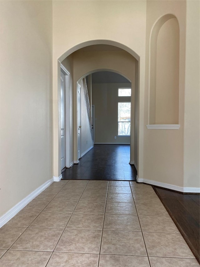 hallway with light tile patterned flooring and a high ceiling