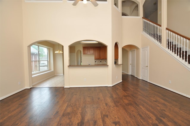 9210 Hidden Lake E Lake E, Magnolia, TX 77354 - unfurnished living room with a high ceiling, ceiling fan with notable chandelier, baseboards, and wood finished floors
