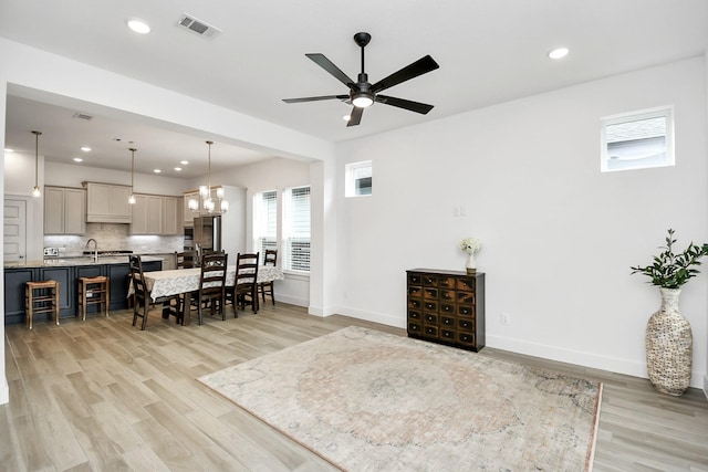 living room with ceiling fan with notable chandelier and light hardwood / wood-style floors