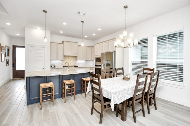 dining space featuring plenty of natural light, a notable chandelier, and light hardwood / wood-style flooring