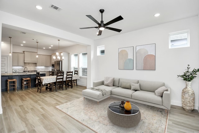 living room with ceiling fan with notable chandelier and light wood-type flooring