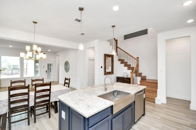 kitchen with blue cabinets, sink, hanging light fixtures, stainless steel dishwasher, and light hardwood / wood-style flooring