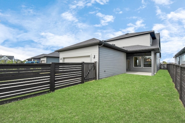 back of house featuring a patio, a lawn, and a garage