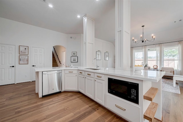 kitchen featuring pendant lighting, white cabinetry, black microwave, an island with sink, and stainless steel dishwasher