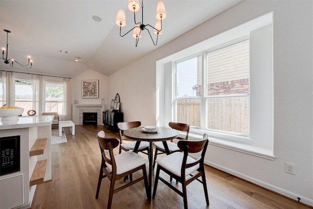 dining area featuring an inviting chandelier, light hardwood / wood-style flooring, and lofted ceiling