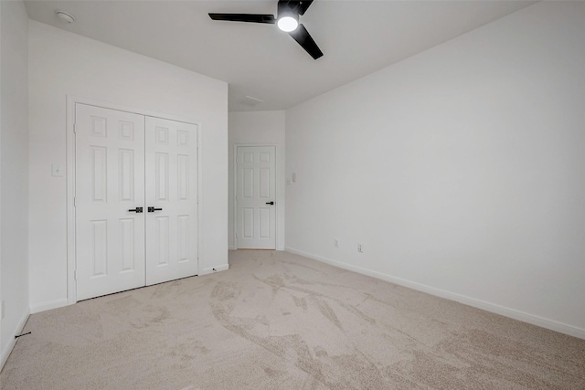 unfurnished bedroom featuring ceiling fan, a closet, and light carpet