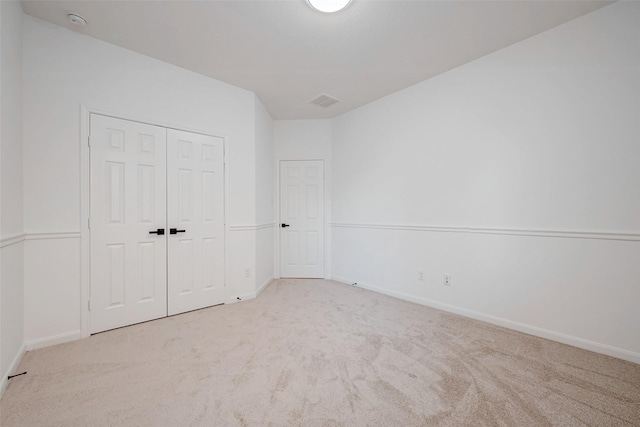 unfurnished bedroom with light colored carpet and a closet