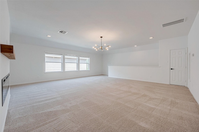 carpeted empty room with an inviting chandelier