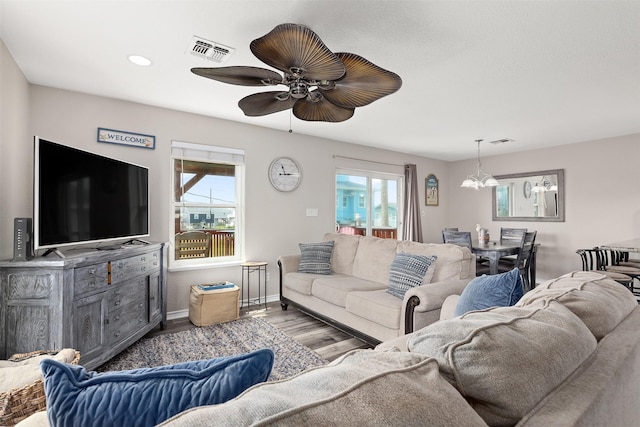 living room with wood-type flooring and ceiling fan with notable chandelier