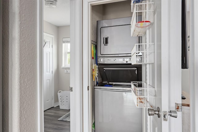 washroom with stacked washer and dryer and hardwood / wood-style floors